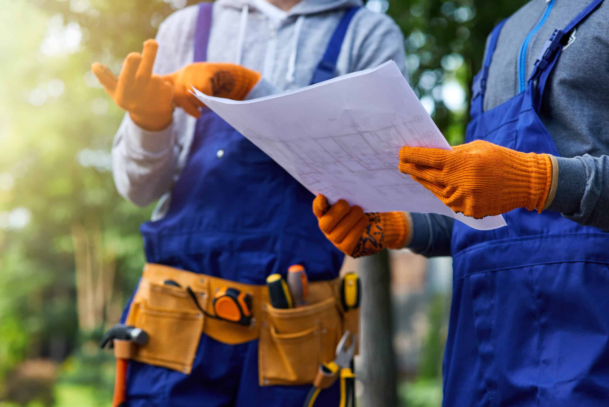 Maintenance workers reviewing a property blueprint outdoors